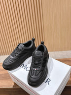 Black Moncler sneakers, side and front view, with lace eyelets and logo patch.