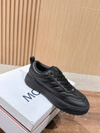 Black Moncler low-top sneakers with side stripe detailing and lace-up front.