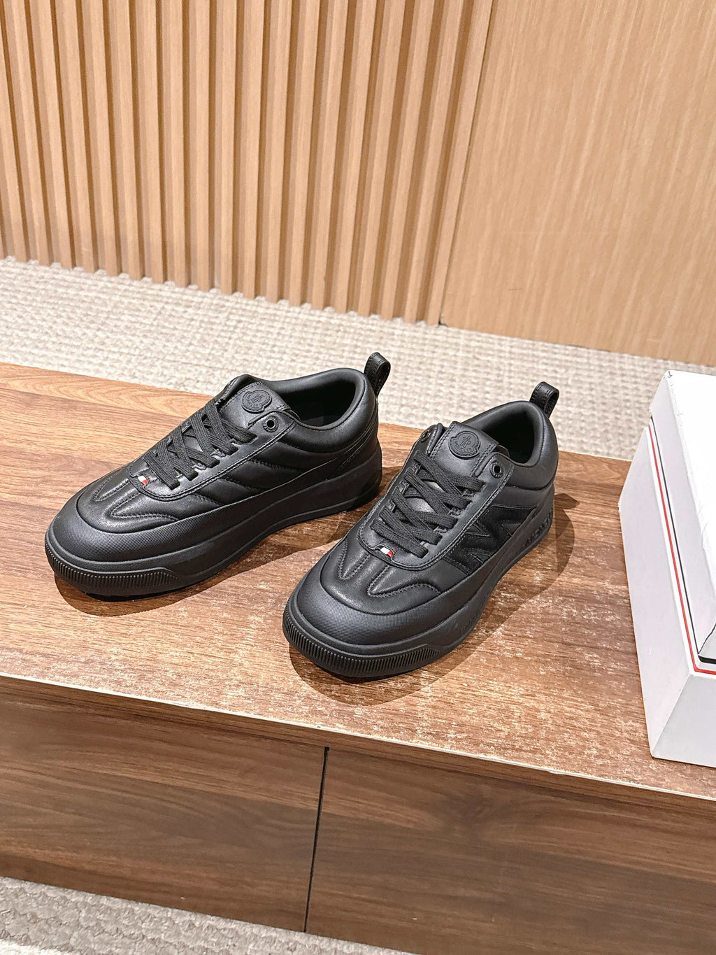 Pair of black Moncler low-top sneakers on display with lace-up uppers.