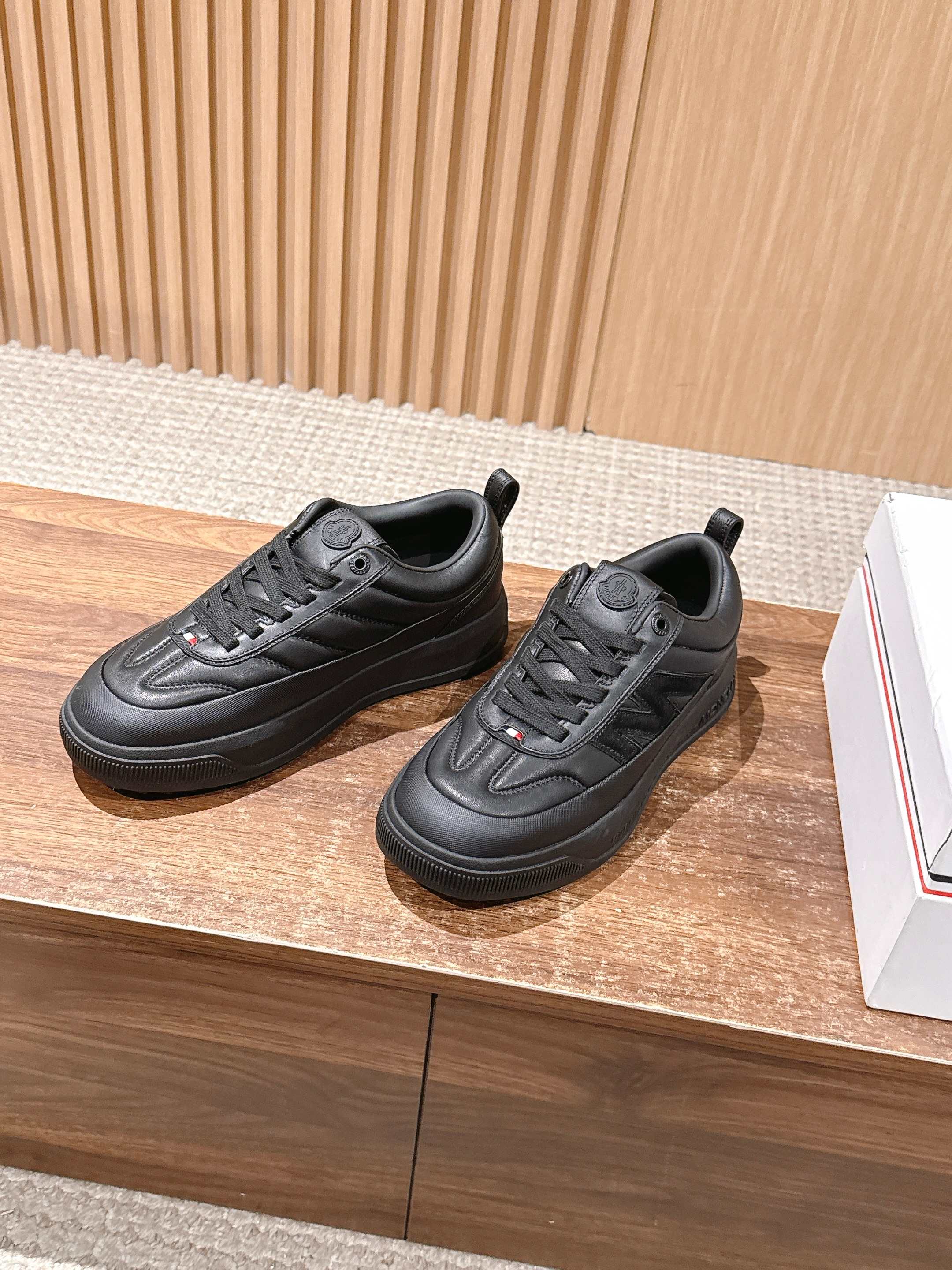 Pair of black Moncler low-top sneakers on display with lace-up uppers.
