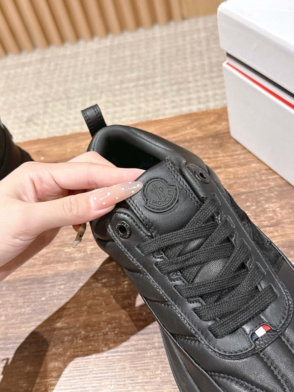 Black Moncler sneaker heel with embossed badge and lace-up front.