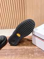 Black Moncler sneaker outsole with ribbed tread and small yellow accent.