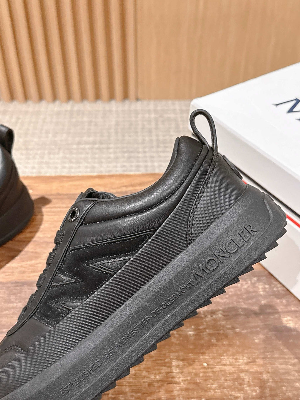 Black Moncler sneakers with stitched side panel and lace-up design.
