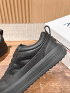 Black Moncler sneakers with stitched side panel and lace-up design.