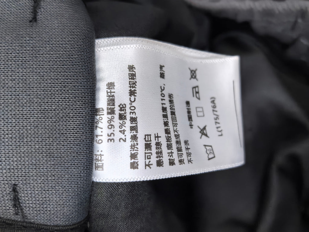 Dark gray Louis Vuitton pants care label with fabric composition and wash symbols