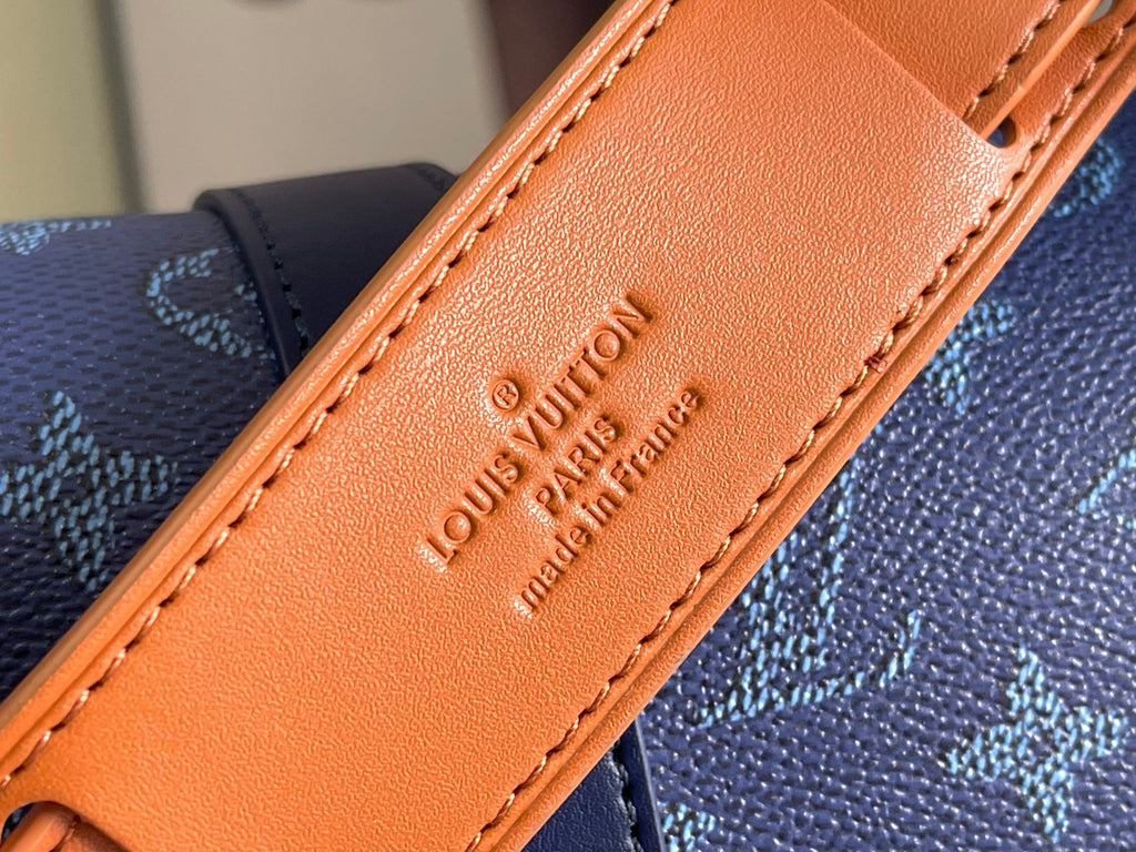 Orange leather trim close-up with Louis Vuitton stamped text and stitched edge