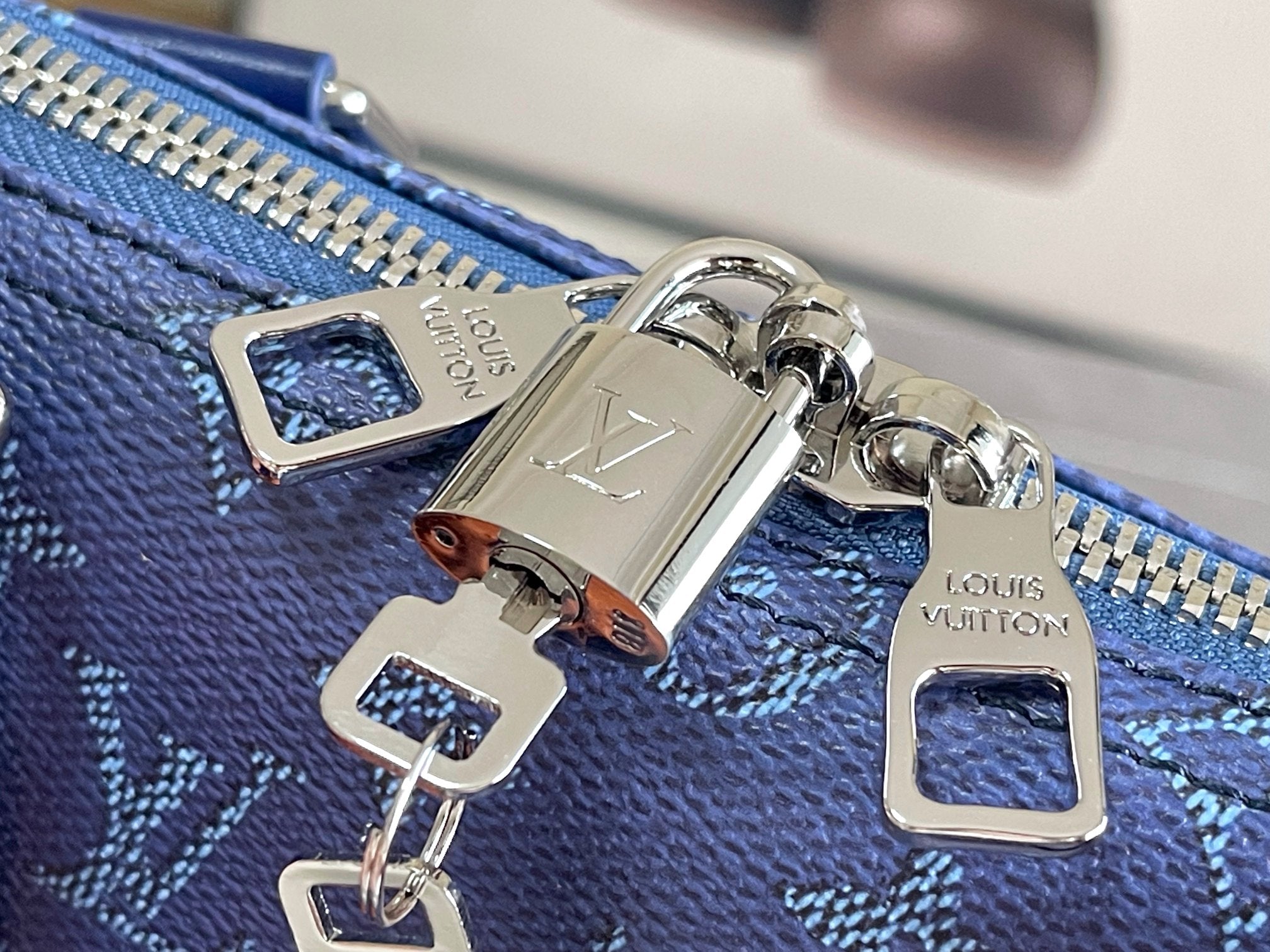 Blue monogram bag zipper pull and metal hardware with engraved logo plates