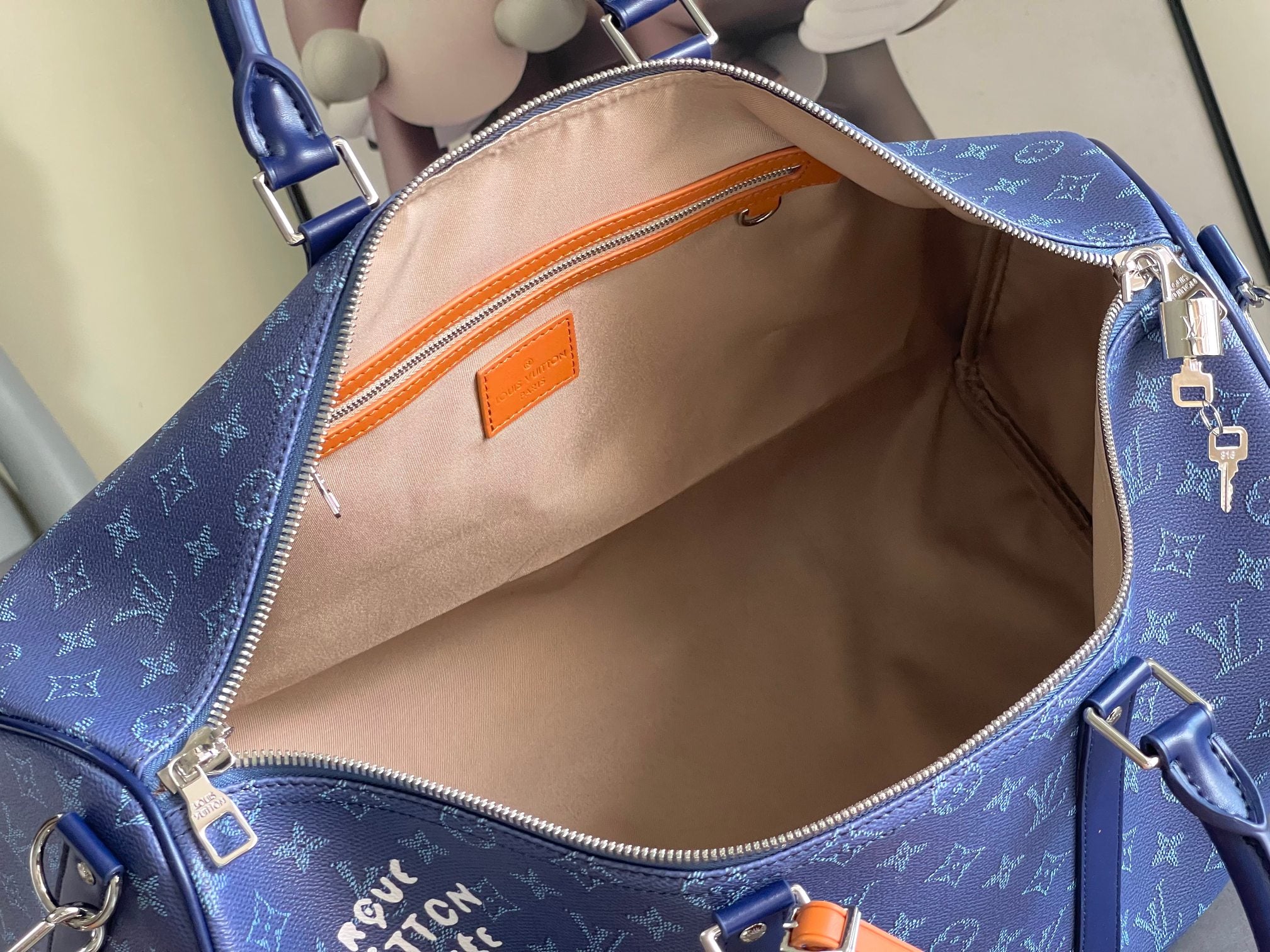 Open Louis Vuitton blue duffel bag with beige lining, inner zipper pocket, orange trim