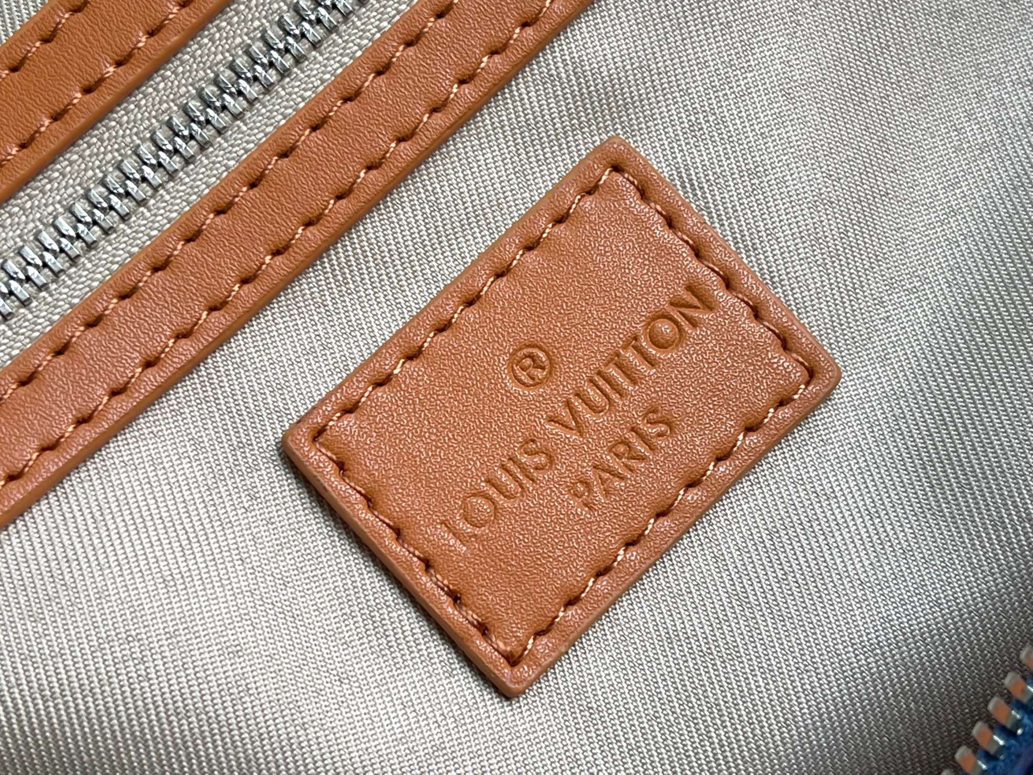 Louis Vuitton label patch on bag, brown leather tag with embossed “Louis Vuitton” text