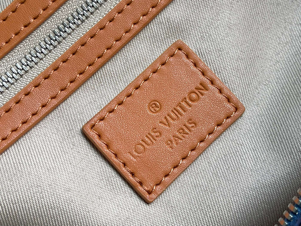 Louis Vuitton leather logo patch on blue bag zipper panel with brown stitching