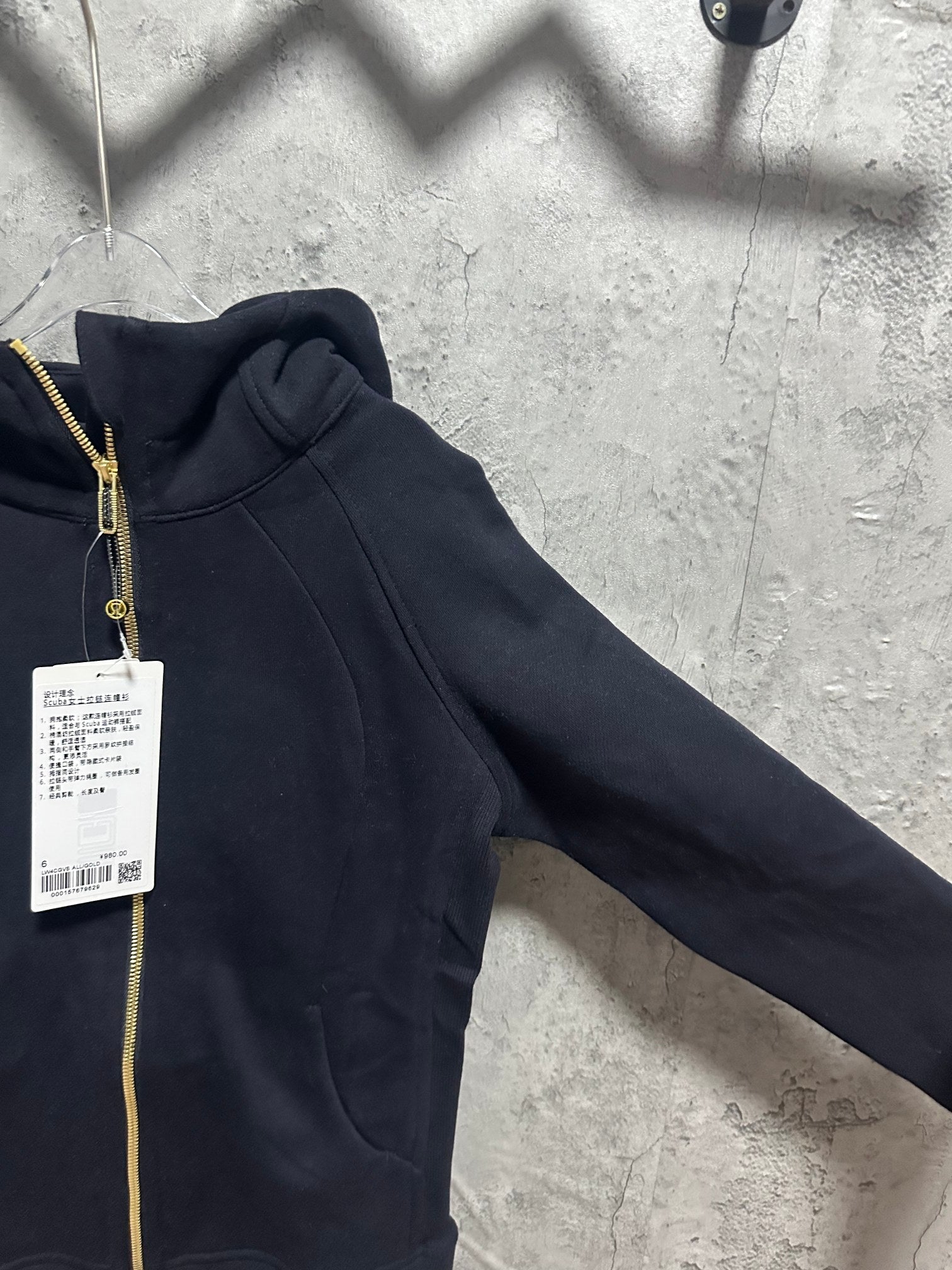 Dark zip-up hoodie sleeve and hood with side seam and gold zipper edge