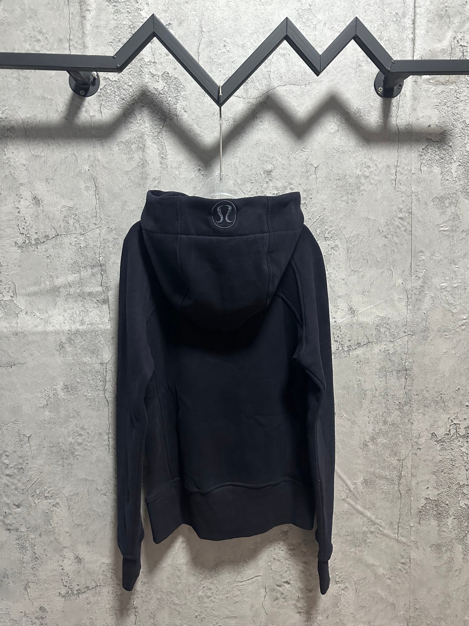 Dark zip-up hoodie with hood and stitched logo on back yoke