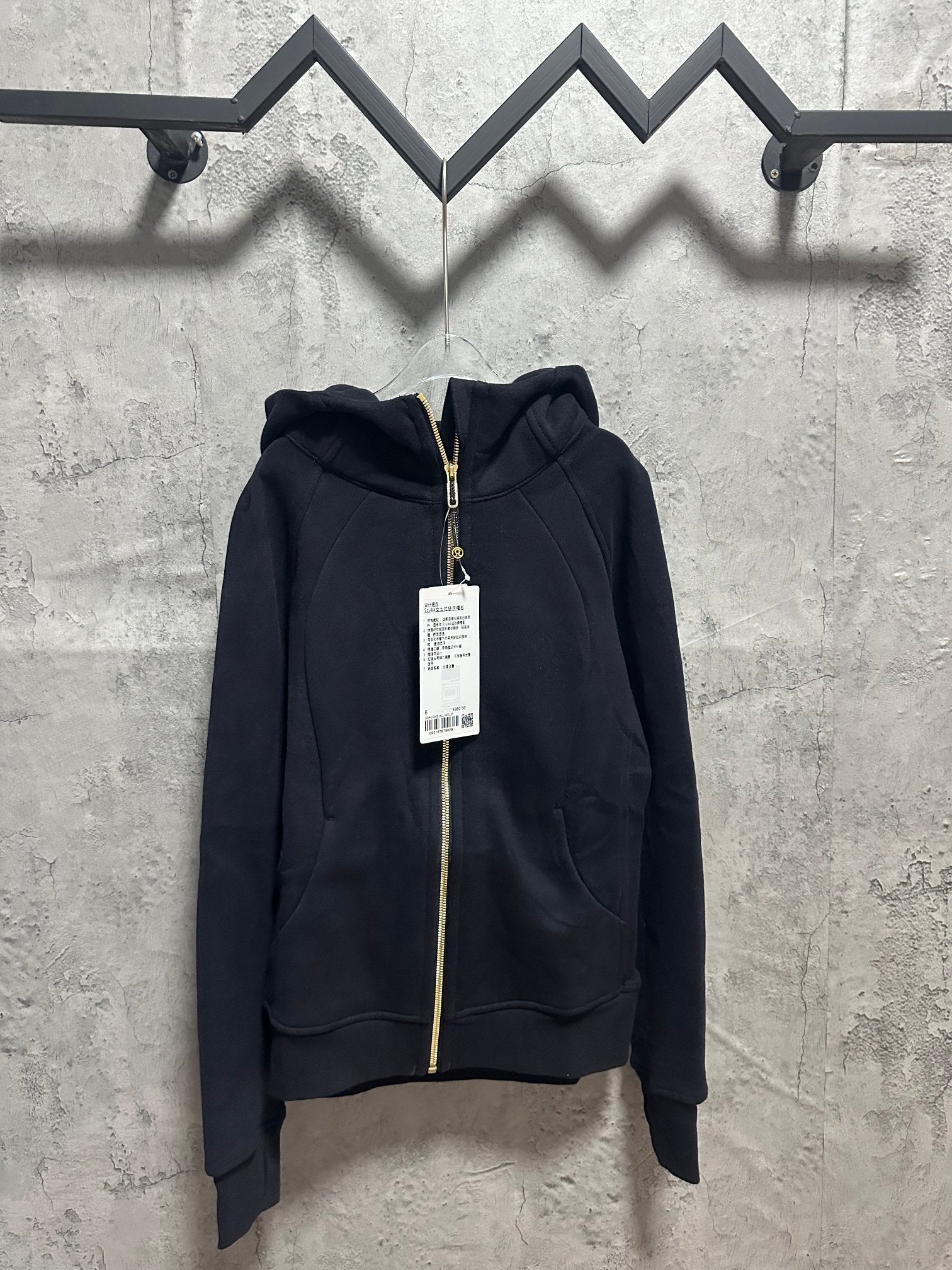 Dark zip-up hoodie with hood, gold zipper, and front pockets