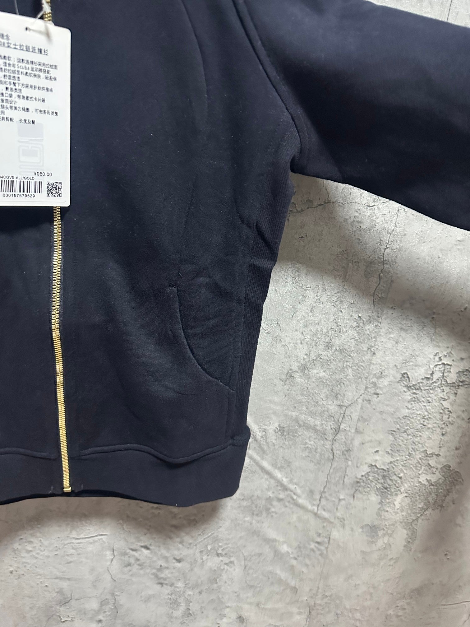 Dark zip-up hoodie front with kangaroo pocket and gold zipper trim