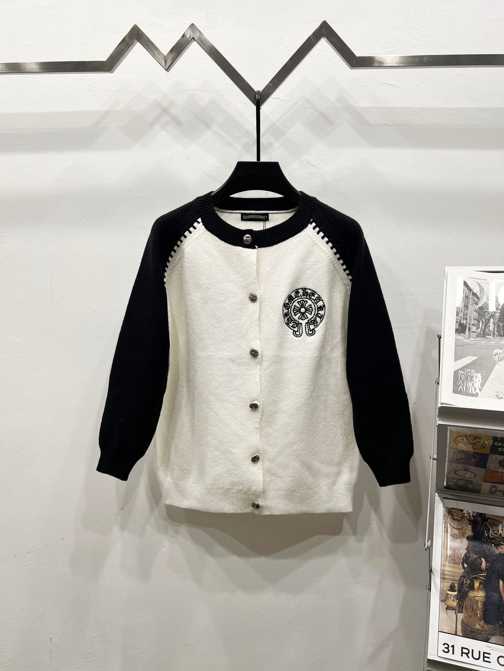 Black-sleeve white raglan cardigan with button front and chest crest patch.