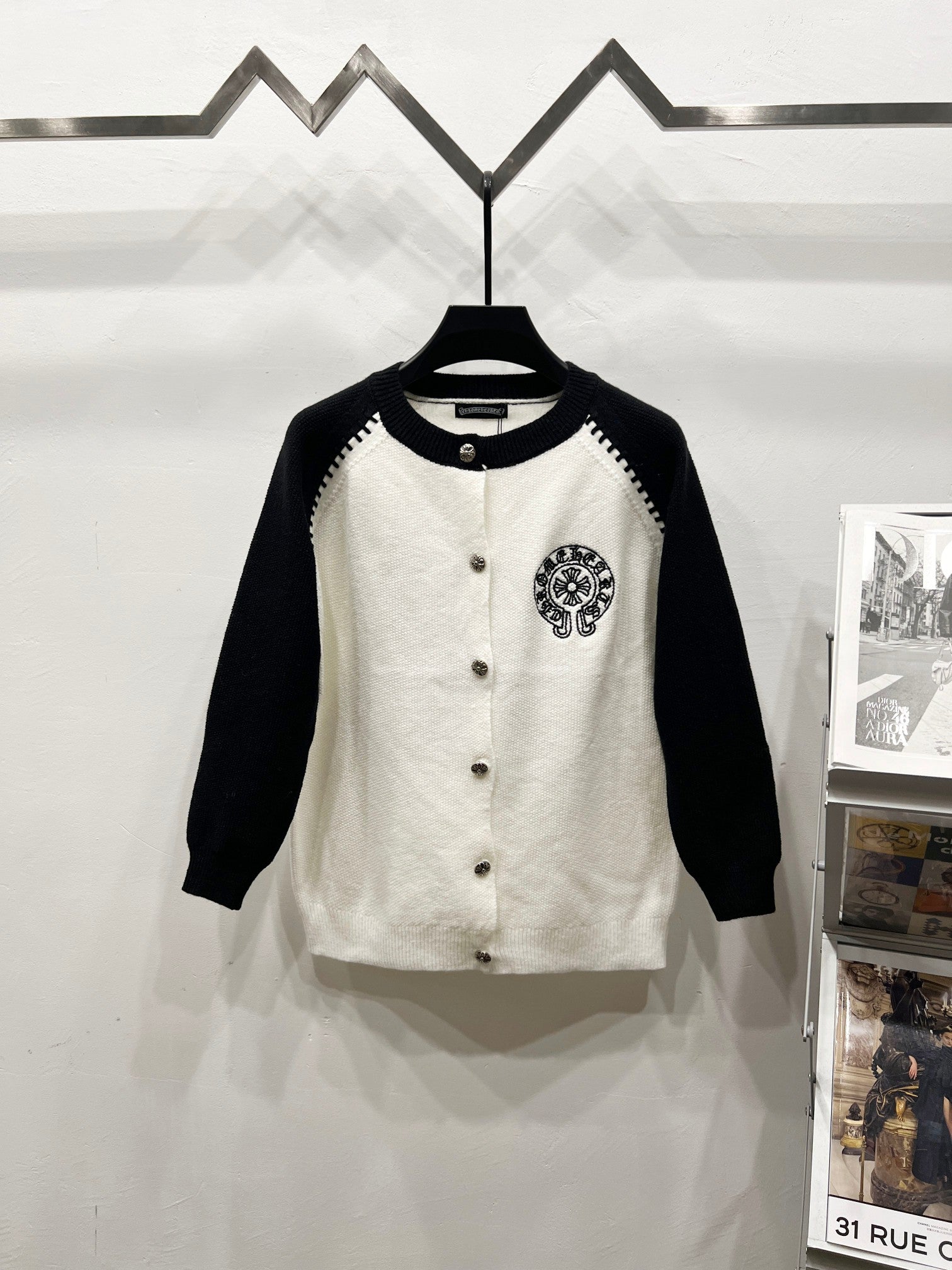 Black-sleeve white raglan cardigan with button front and chest crest patch.