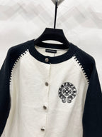 White raglan cardigan with navy crew neck, button placket, and small crest patch.