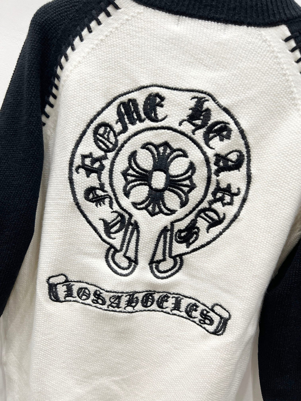 White raglan cardigan with crest mascot emblem and banner text patch.