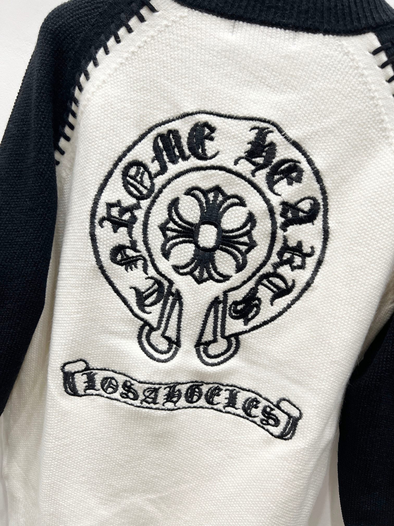 White raglan cardigan with crest mascot emblem and banner text patch.