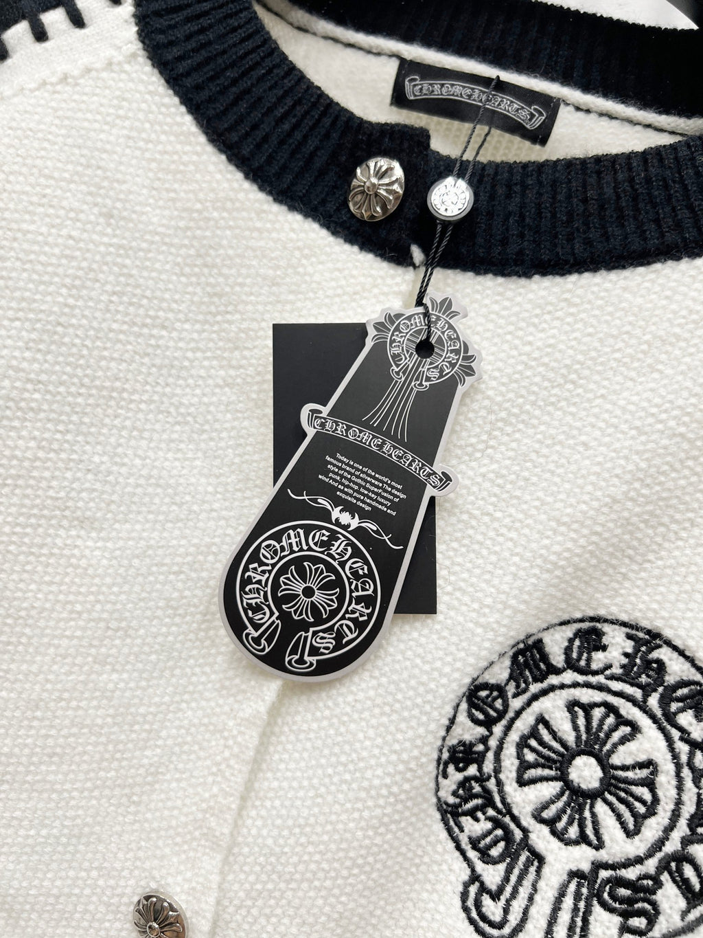 Ribbed navy neckline with metal snap buttons on white raglan cardigan.