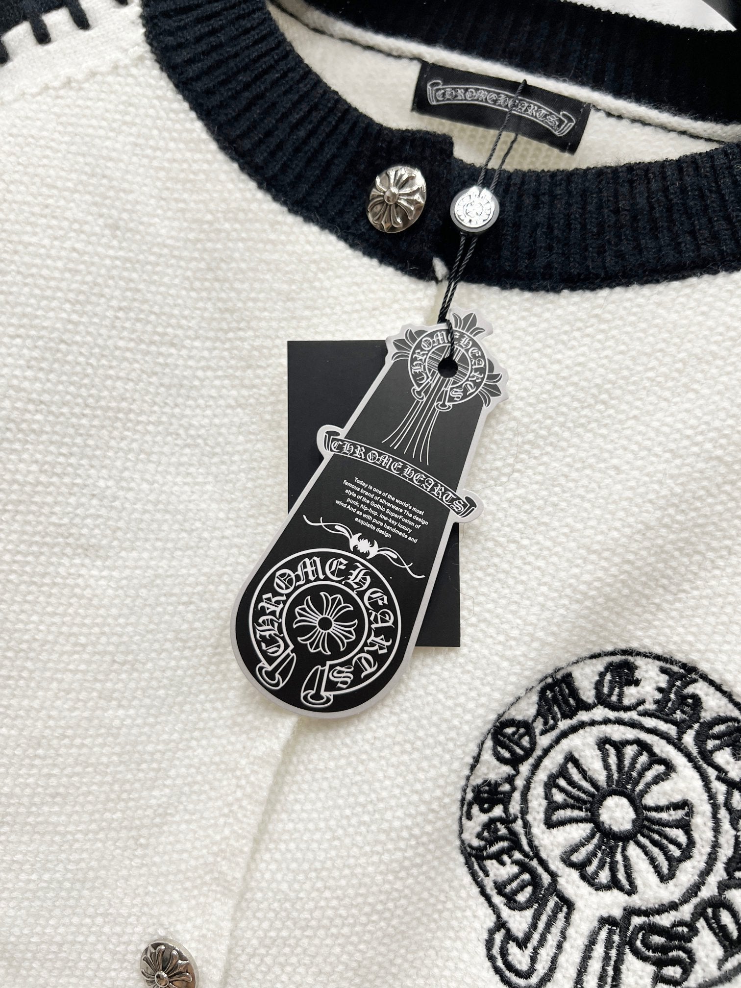 Ribbed navy neckline with metal snap buttons on white raglan cardigan.