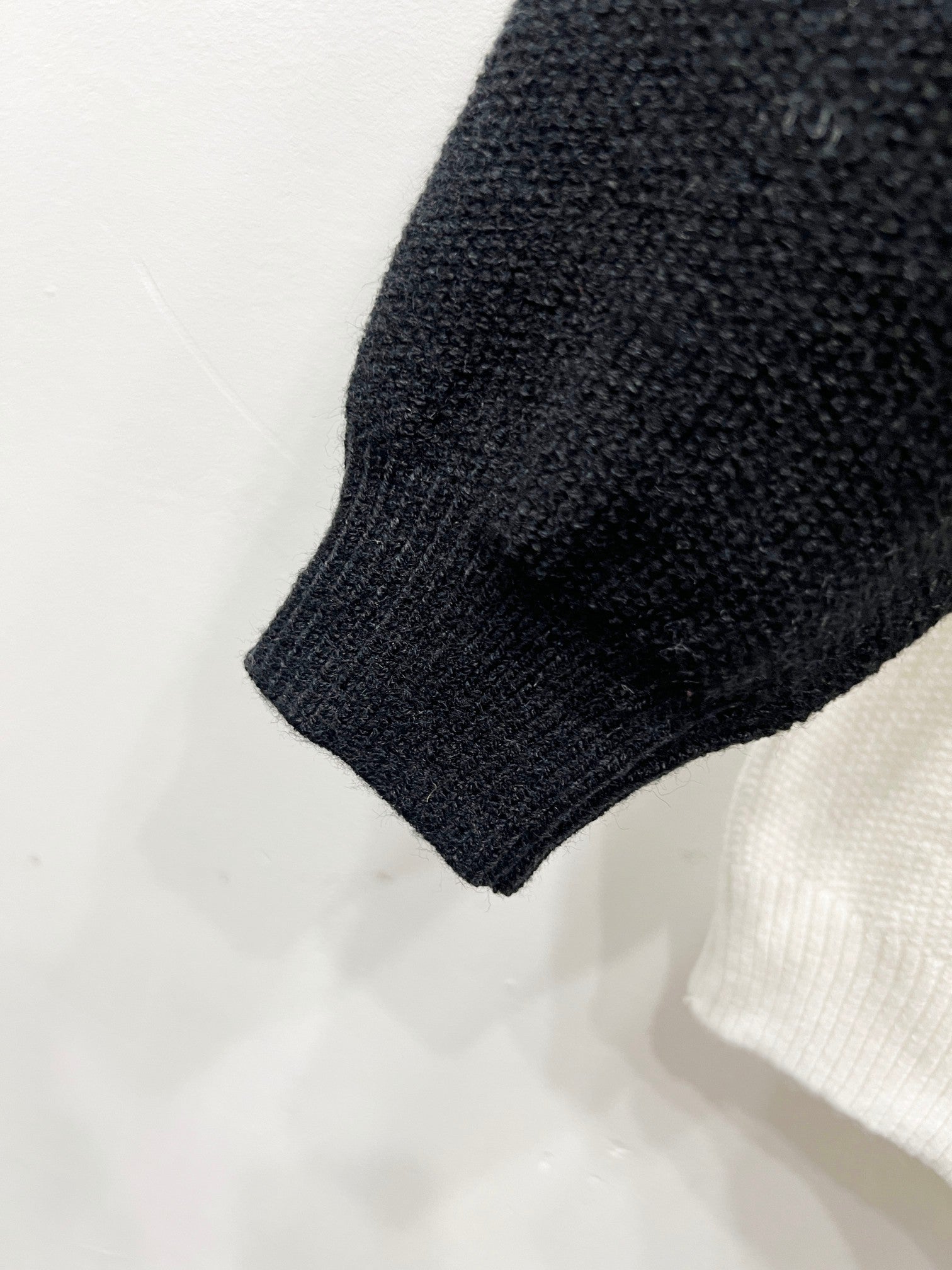 Knit black sleeve cuff and hem on white raglan cardigan.