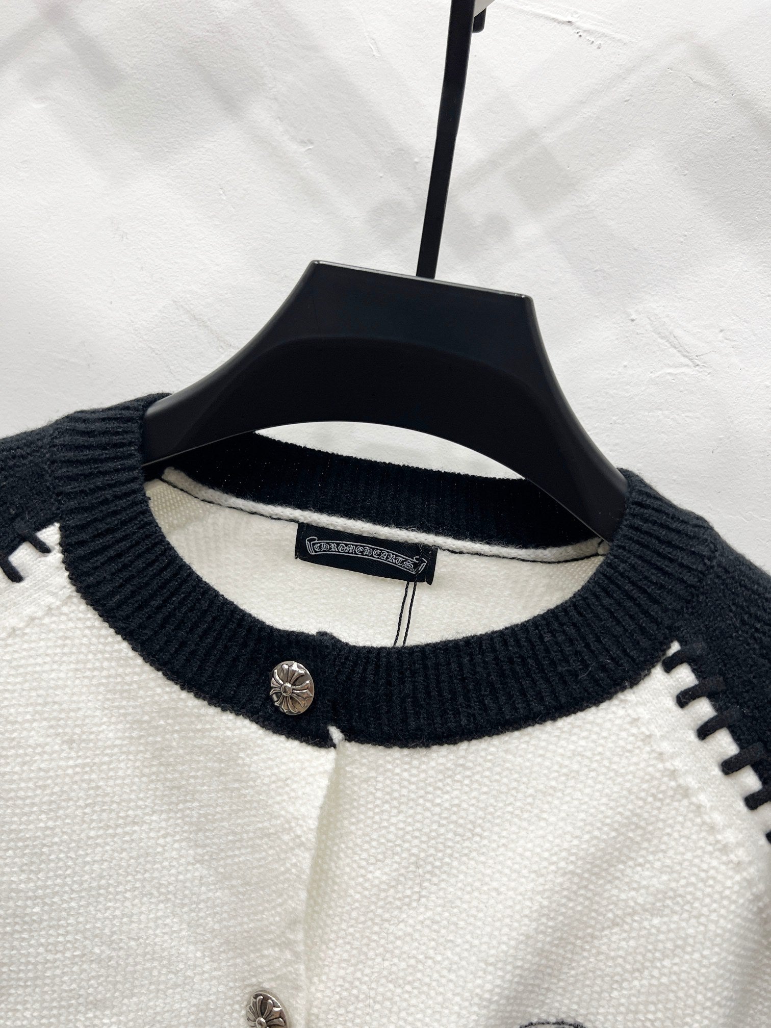 White cardigan with navy ribbed crew neck and buttoned placket.