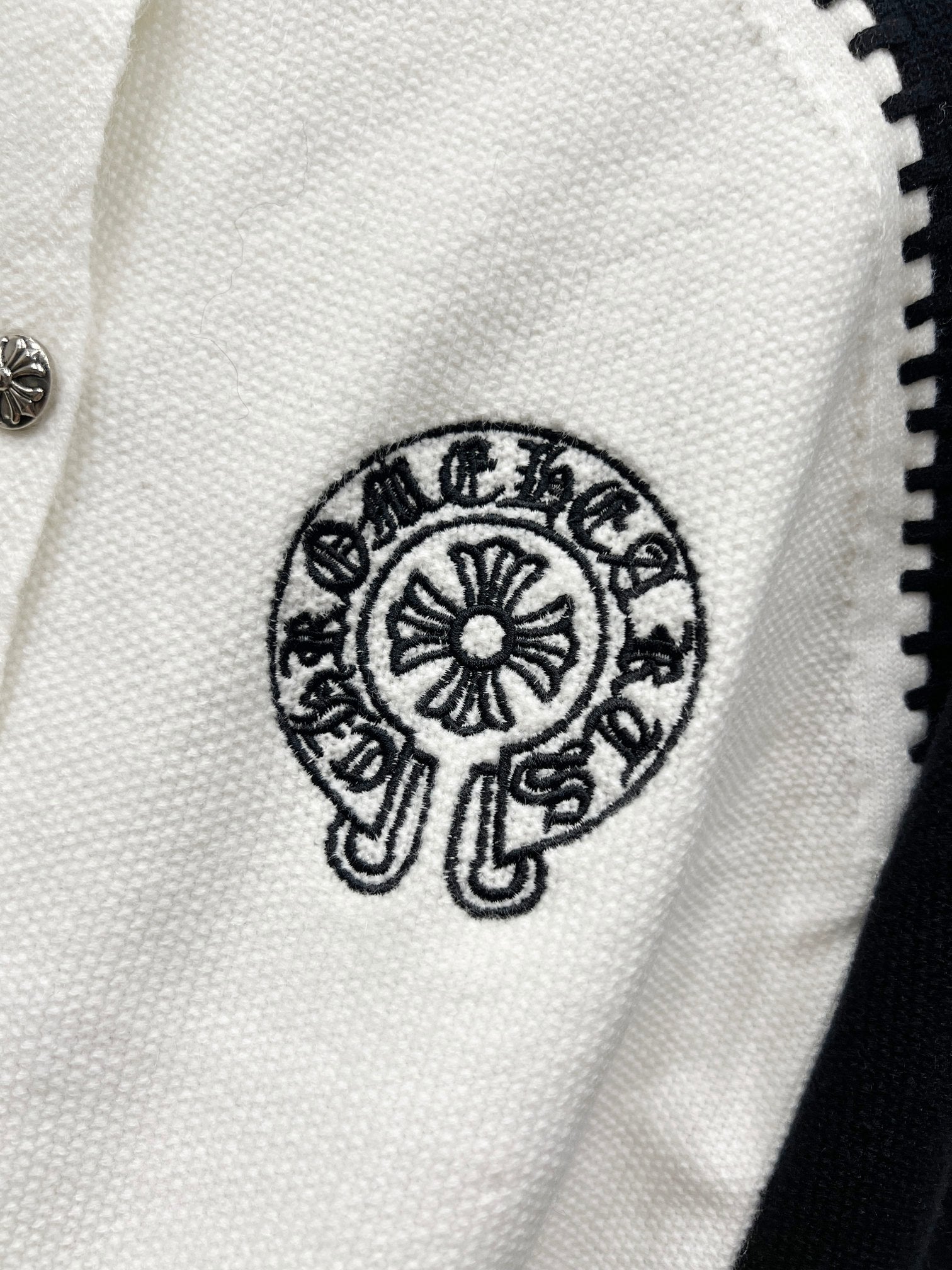White raglan cardigan with circular crest logo print.
