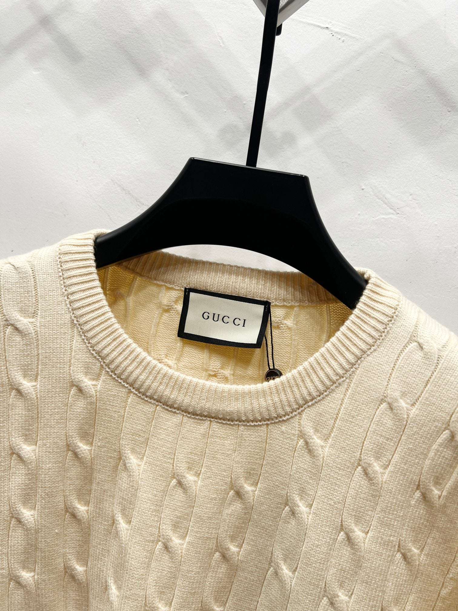 Cream cable-knit sweater neckline with Gucci label