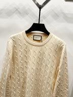 Cream cable-knit sweater with ribbed crew neck and textured knit pattern