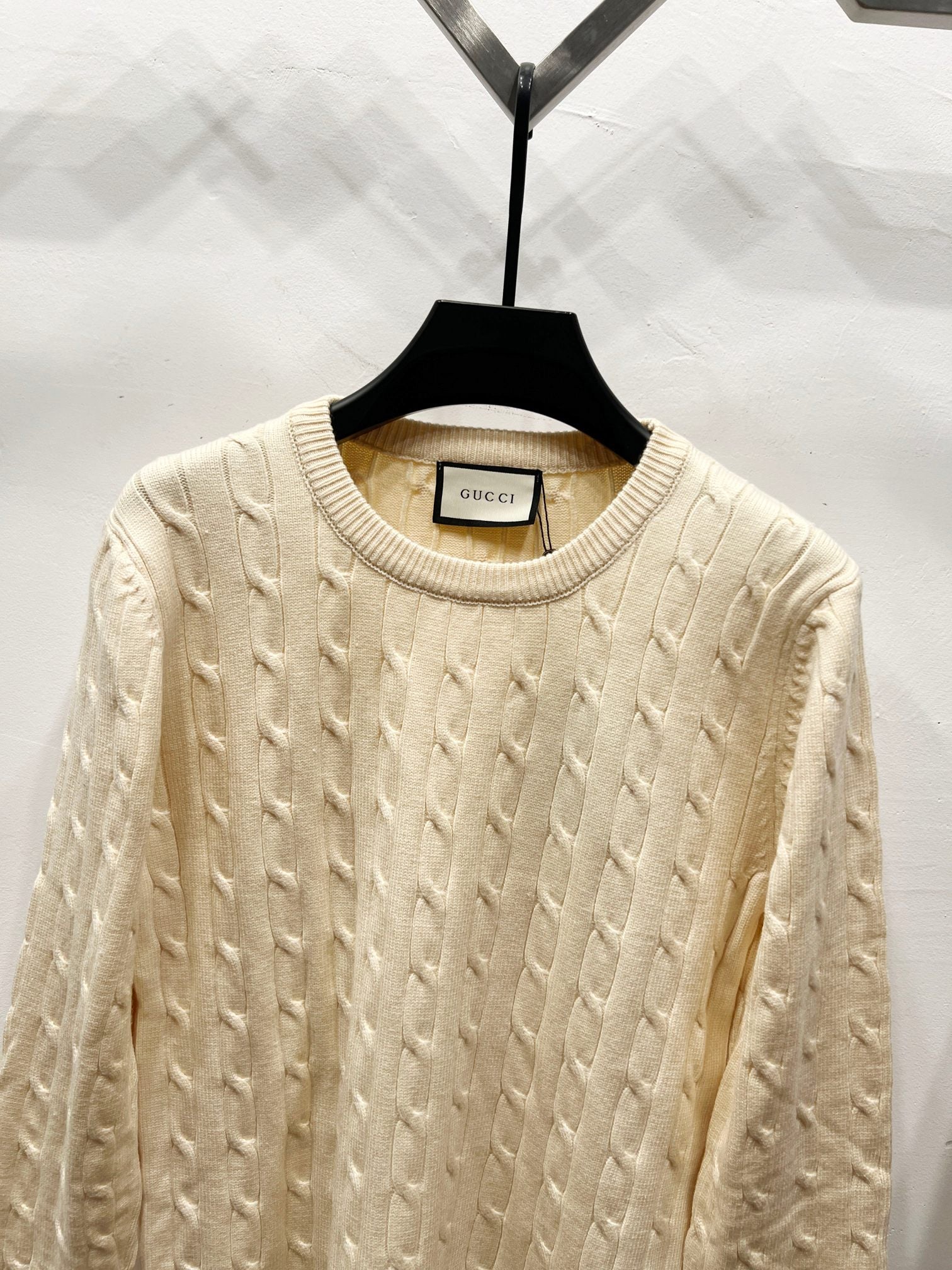 Cream cable-knit sweater with ribbed crew neck and textured knit pattern