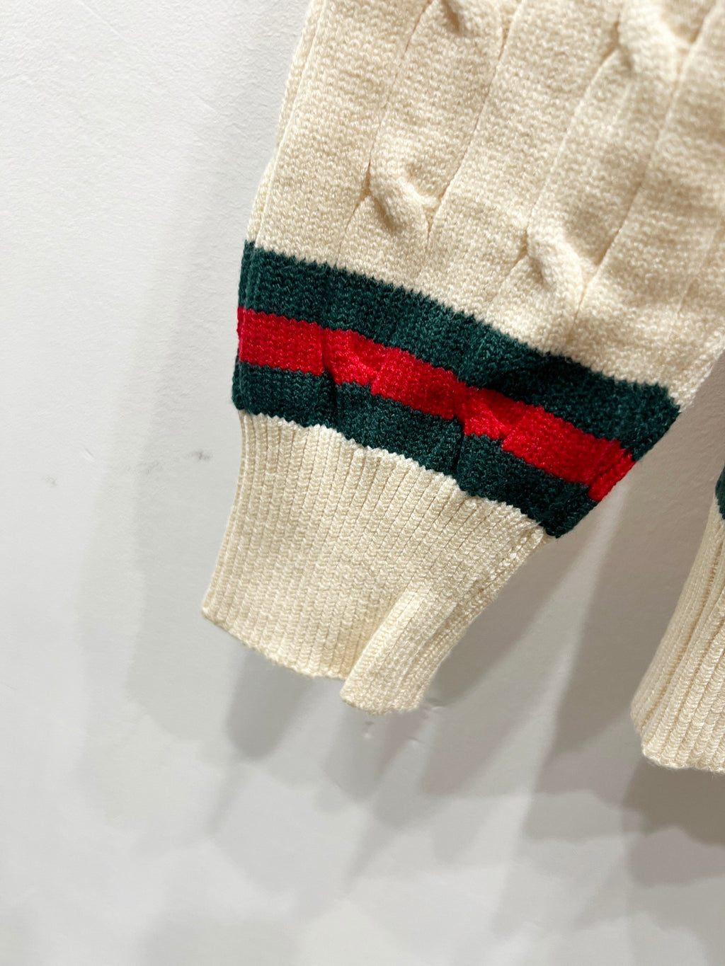Cream knit sweater sleeve with red, green, and dark striped cuff