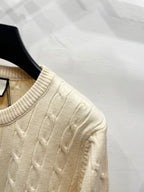 Cream cable-knit sweater sleeve with textured stitch and ribbed cuff