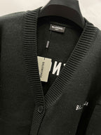 Balenciaga black knit cardigan detail with ribbed edge and front logo tag