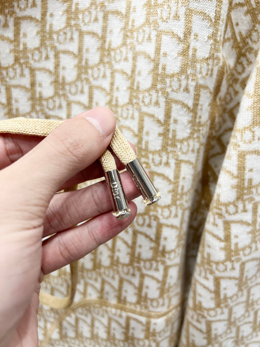 Beige logo-pattern hooded jacket with gold-tone zipper and metal pull tab