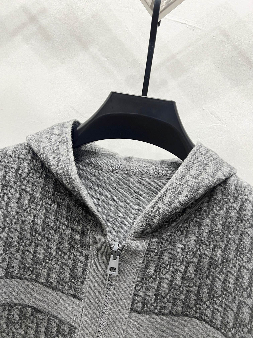Grey hooded zip jacket close-up of zipper and hood lining with repeating logo pattern