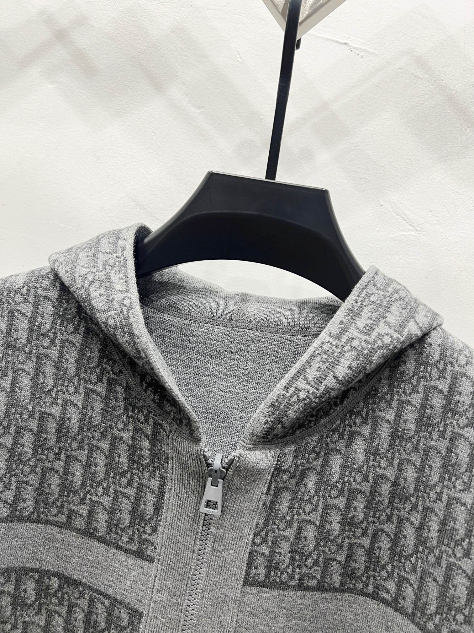 Grey hooded zip jacket close-up of zipper and hood lining with repeating logo pattern