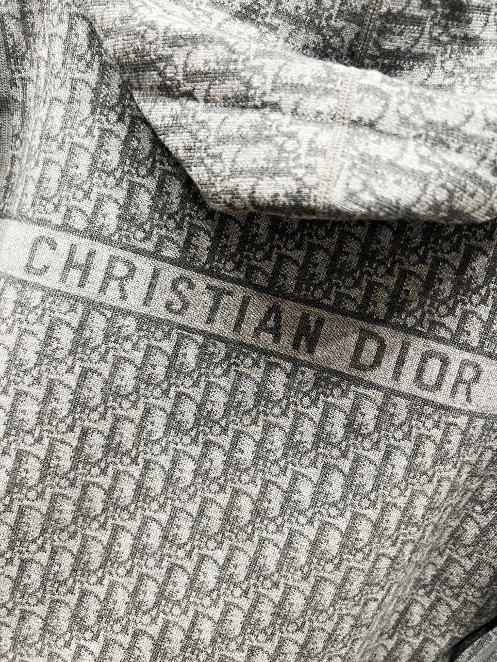 Close-up of grey fabric with Dior-style lettering pattern across the hood