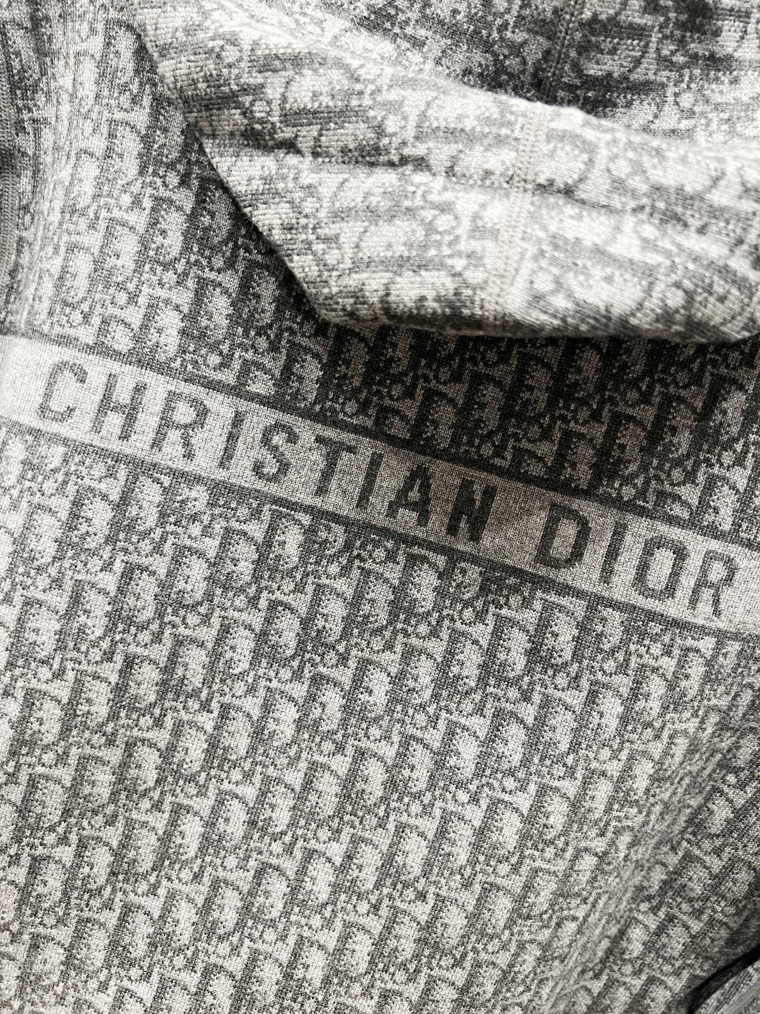 Close-up of grey fabric with Dior-style lettering pattern across the hood