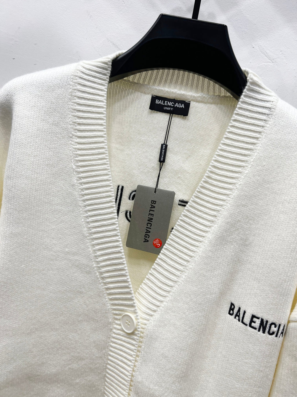 Cream knit V-neck cardigan on hanger with BALENCIAGA sleeve logo