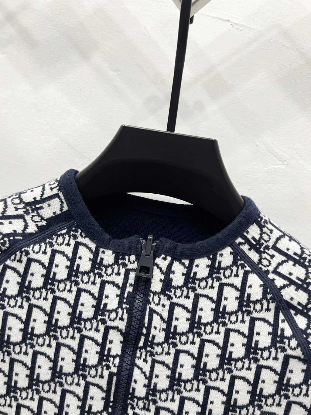 Close-up of black-and-white Dior logo zip jacket, knit collar and placket