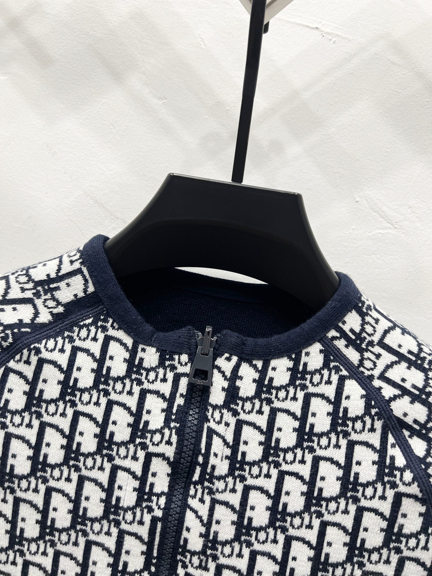 Close-up of black-and-white Dior logo zip jacket, knit collar and placket