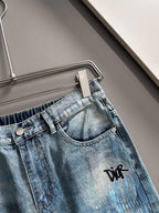 Light blue denim jeans detail: curved waistband, button closure, black logo on leg