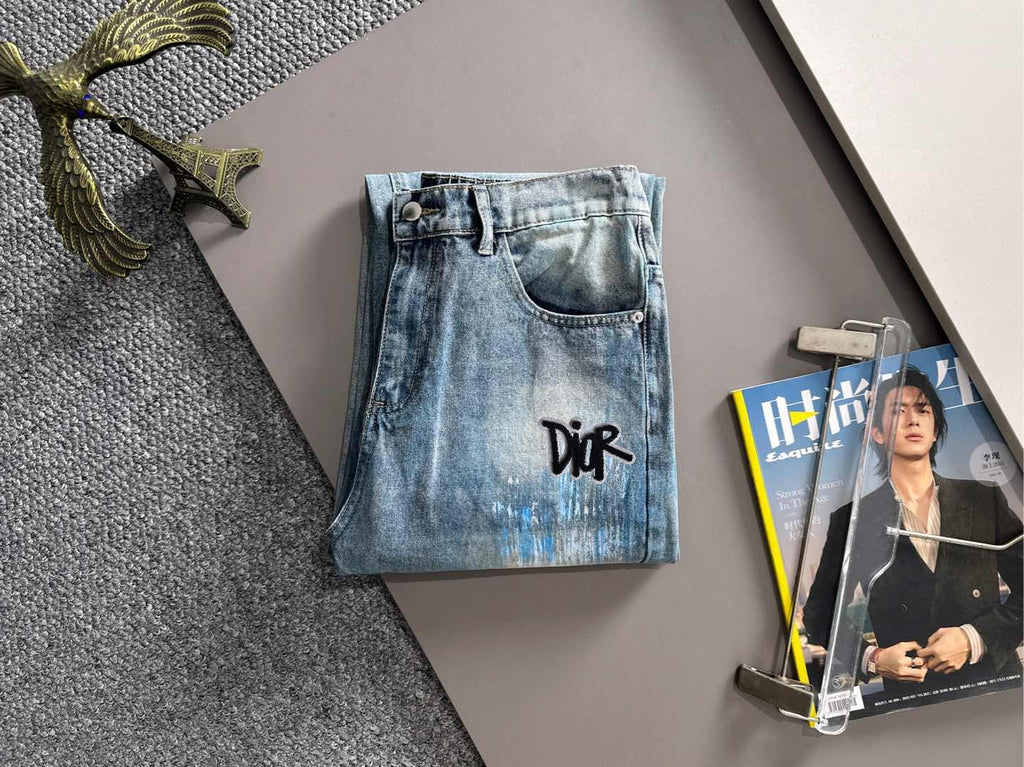Medium blue wash denim jeans with black logo on front pocket area, button fly