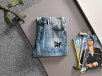 Medium blue wash denim jeans with black logo on front pocket area, button fly