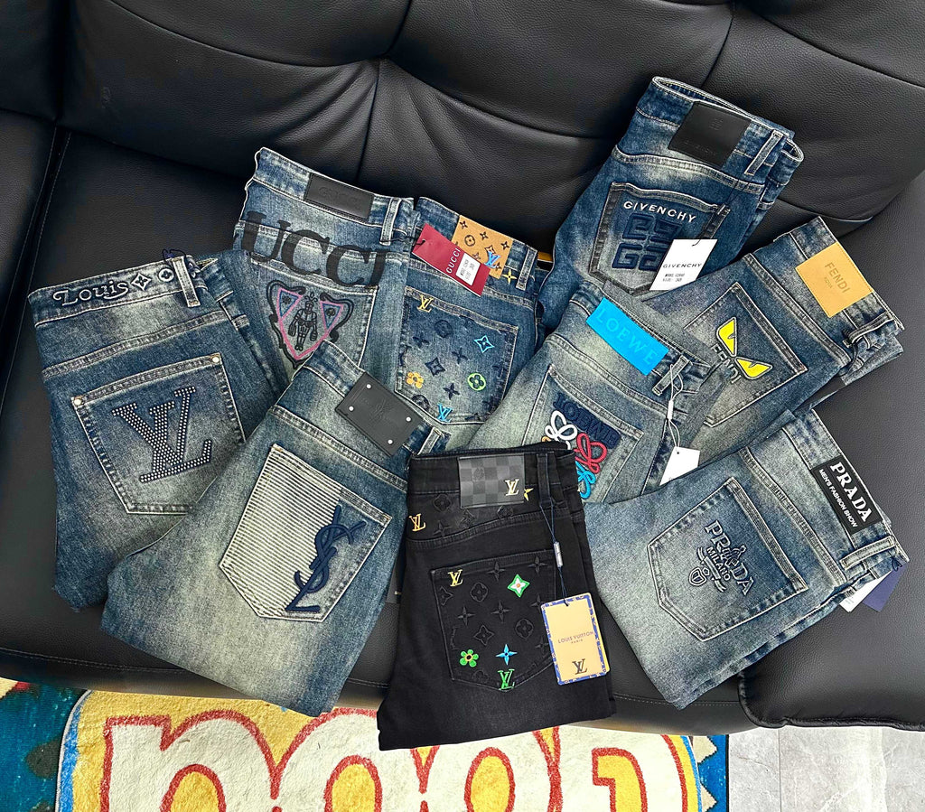 Assorted blue denim designer pants displayed on a couch with price tags