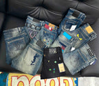 Assorted blue denim designer pants displayed on a couch with price tags