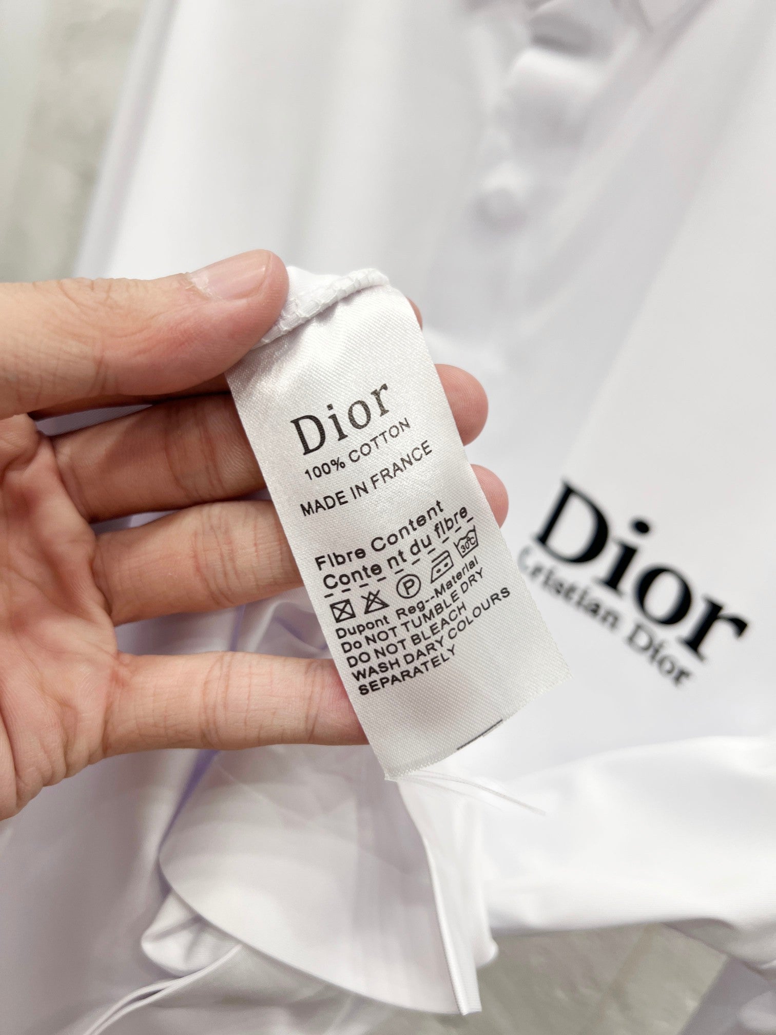 White fabric care tag with Dior branding and fiber content text