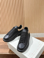 Black leather sneakers with gold glitter heel overlay, lace-up front