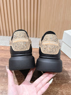 Back view of black sneakers with gold glitter heels and thick rubber sole